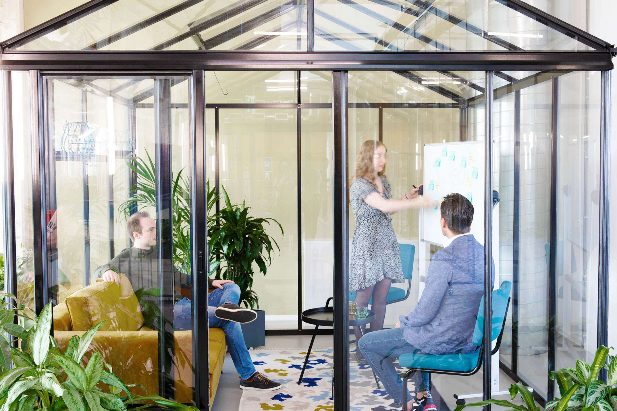 een groep mensen die in een kamer met glazen wanden zit